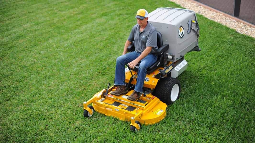 Man mowing a lawn with a Walker Model T mower